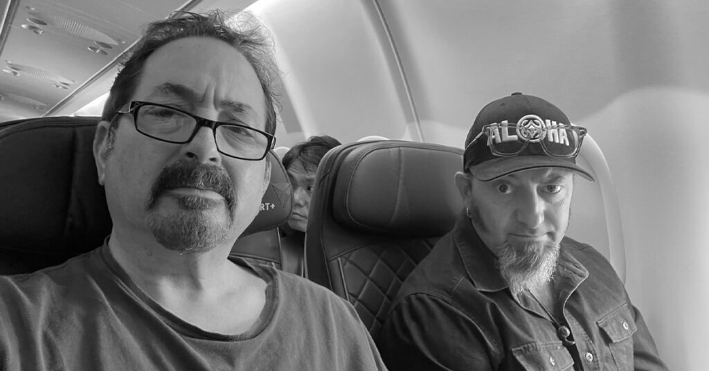 Ron Small and Felix Arceneaux onboard a jet airliner bound for Japan.